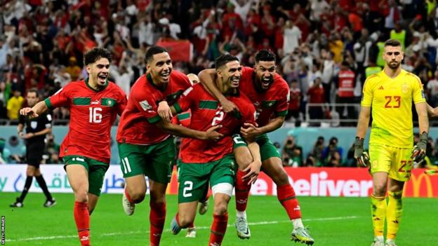 Achraf Hakimi celebrates with his Morocco teammates as a dejected Unai Simon looks on